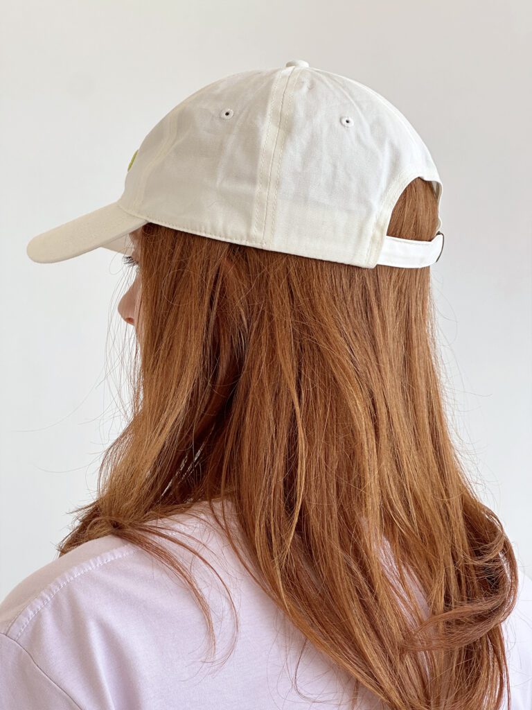 Woman wearing Ringo Studio lavender tee and Ringo Studio white cap with clasp.