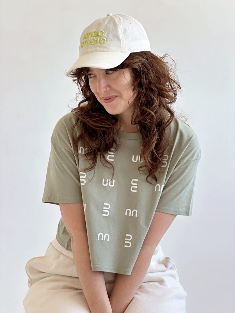Woman wearing pistachio crop tee with white coloured Ringo Studio cap with lime coloured embroidered Logo.