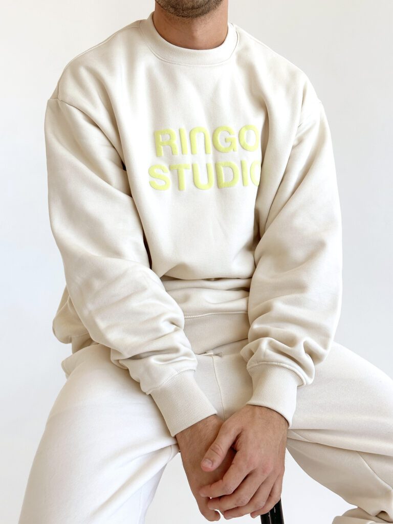 Model wearing Ringo Studio puff-print beige sweatshirt and sweatpants .