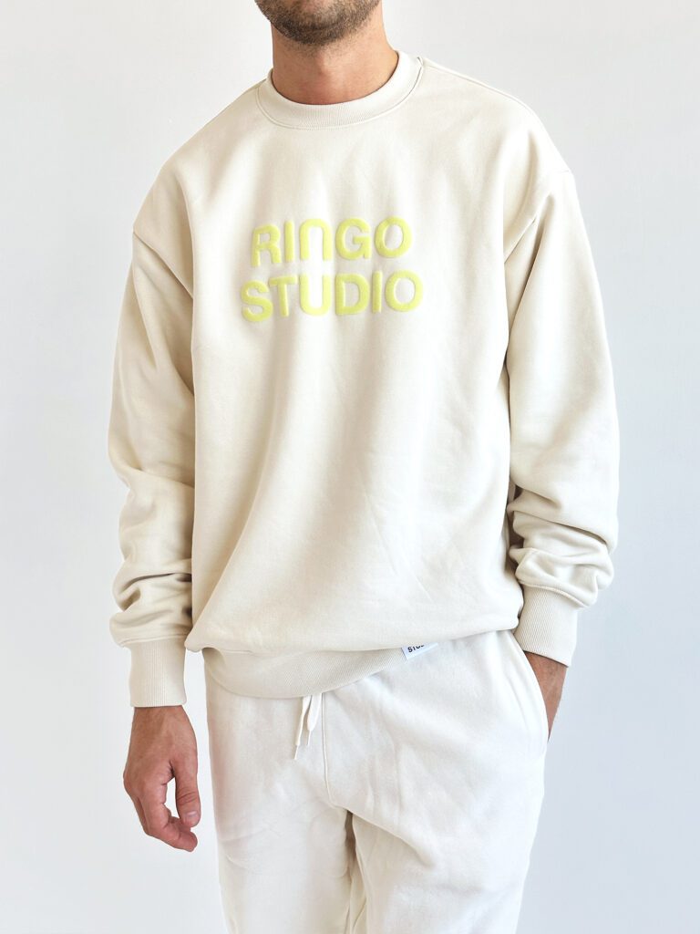 Model wearing Ringo Studio puff-print beige sweatshirt and sweatpants .