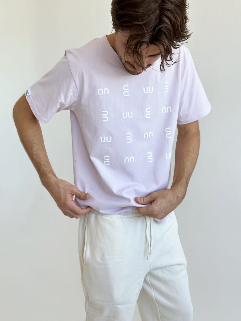 Man wearing Ringo Studio Lavender Tee with Ringo Studio monogram textured pattern, paired with beige sweatpants for a casual chic look.